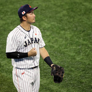 身穿球衣的日本棒球選手在球場上戴著手套並握拳。 — 運動 壁紙