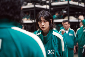 身穿綠色遊戲運動服、號碼067的年輕參賽者在比賽中專注凝視。 — 067 魷魚遊戲 壁紙