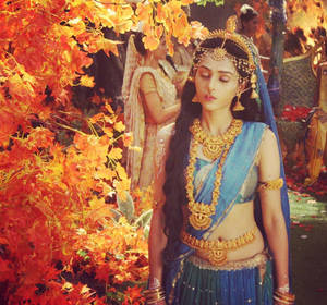 穿著傳統印度服飾的女性被秋葉環繞 — Maa Durga 壁紙