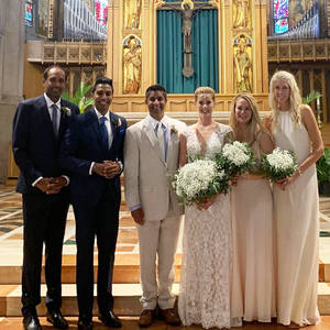 婚禮派對在教堂內微笑，身後是彩繪玻璃和金色祭壇。 — 羽球 壁紙