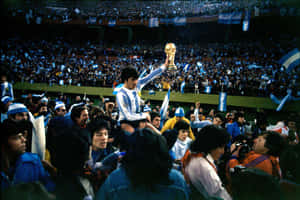 足球員在夜間體育場人群中高舉世界盃獎盃 — FIFA 世界盃 壁紙