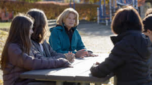 女性在秋日公園的野餐桌旁與孩子們交談 — 寒冷 壁紙