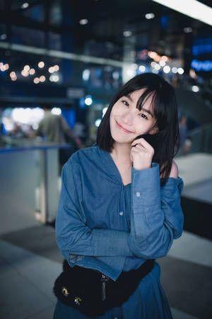 年輕女性在夜晚的現代室內空間中穿著藍色牛仔套裝微笑。 — 女演員 壁紙