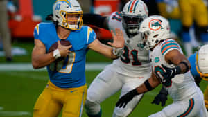 NFL四分衛帶球奔跑，防守球員在草地上擒抱他。 — 運動 壁紙