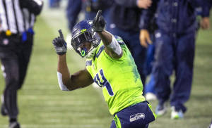 美式足球員在雨夜球場上舉起食指慶祝。 — Dk Metcalf 壁紙