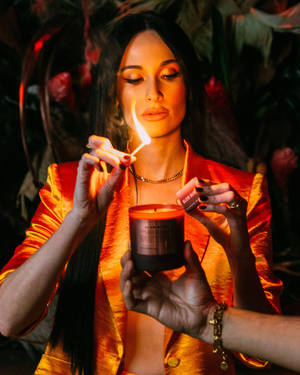 女性在溫暖光線的房間裡點燃蠟燭，房間有花卉裝飾。 — 蠟燭 壁紙