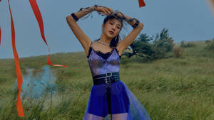 一位身穿藍色閃亮服裝的女性在田野中擺姿勢，周圍有紅色絲帶和藍色煙霧。 — 模特兒 壁紙