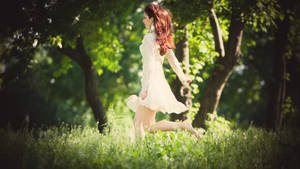 身穿白色連衣裙的女性在有樹木的陽光草地上跳躍 — Running 壁紙