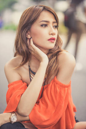 一位身穿橙色上衣的女性在日落時分在戶外若有所思地擺姿勢。 — 模特兒 壁紙