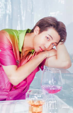 身穿彩色襯衫的年輕男子將手臂擱在放有酒杯的桌子上 — BTS RM 壁紙