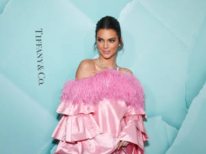 身穿粉紅色羽毛長裙的女性在 Tiffany & Co. 活動中擺姿勢。 — 坎達兒·珍娜 壁紙