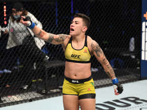 女性MMA拳手身穿黃色裝備在UFC八角籠內慶祝勝利。 — 終極格鬥冠軍賽 壁紙