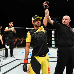 MMA選手在八角籠中慶祝勝利，裁判舉起他的手。 — 終極格鬥冠軍賽 壁紙