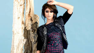 身穿圖案服裝的女性在攝影棚中站在樹幹旁擺姿勢 — 哥德美學 壁紙
