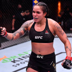 女性MMA拳手在UFC八角籠內慶祝勝利，帶有刺青和手套。 — 運動 壁紙