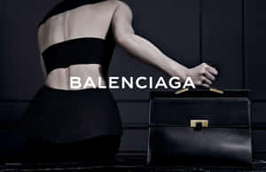 一位黑色時尚模特兒在昏暗的攝影棚中手持Balenciaga手提包。 — 巴黎世家 壁紙