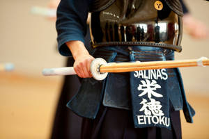 身穿黑色盔甲的武士在室內手持木劍。 — 運動 壁紙