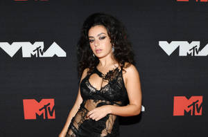 女性身穿黑色蕾絲裙在MTV活動中擺姿勢。