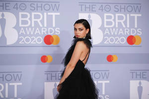 身穿黑色薄紗長裙的女性在2020年全英音樂獎紅地毯活動中擺姿勢。