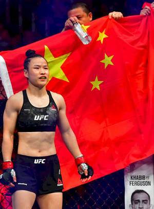 UFC拳手在活動中於中國國旗前手持拳套。 — 運動 壁紙