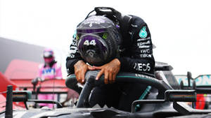 F1車手在比賽後將頭靠在方向盤上的手臂上休息。 — 漢密爾頓 壁紙