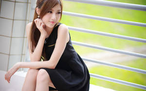 年輕女士穿黑色連衣裙坐在陽台欄杆上，綠色背景 — 模特兒 壁紙