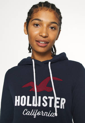 穿著帶有紅色標誌和白色抽繩的深藍色Hollister連帽衫的年輕女性。