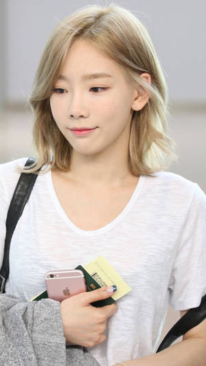 金髮年輕女子在機場手持電話和護照。 — 태연 壁紙
