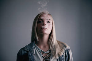 年輕女性在灰色背景的攝影棚中呼出蒸氣。 — 抽菸 壁紙