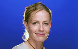 一位金髮女性在藍色背景前溫柔微笑。 — 女演員 壁紙