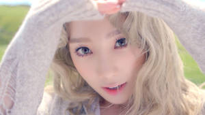 金髮年輕女性在戶外透過雙手窺視。 — 태연 壁紙