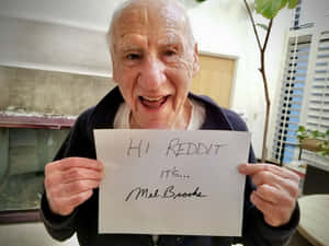 一位長者微笑著手持一張寫著「Hi Reddit It's... Mel Brooks」的便條。 — 搞笑迷因 壁紙