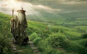 一位長著長長白鬍鬚的老巫師在石徑上穿過綠色山丘。 — 魔戒 壁紙