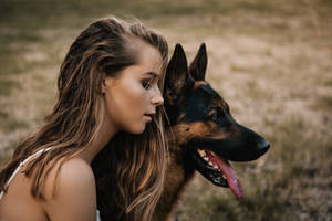 女性與德國牧羊犬在草地上共享寧靜時刻。 — 可愛狗狗 GIF 壁紙