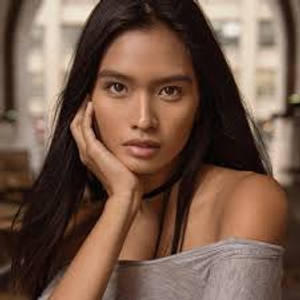 一位長黑髮的女性在室內若有所思地擺姿勢，手靠近臉部。 — 模特兒 壁紙