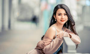 一位穿著粉紅色外套的微笑女性在城市街道上倚靠欄杆。 — 女孩 壁紙