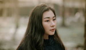 長黑髮的年輕女性在戶外若有所思地凝視。 — 黑色卡通女孩 壁紙