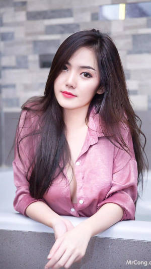 年輕女性穿粉紅襯衫靠著戶外石緣 — 美學粉色GIF 壁紙