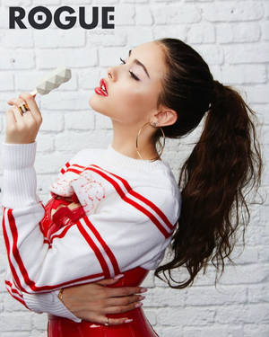 身穿紅白衣服的女性在白色磚牆前吃冰淇淋。 — 麥迪遜·比爾 壁紙