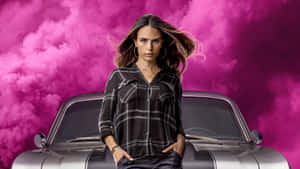 穿著格子襯衫的女性站在經典汽車前，背景是粉紅色煙霧。 — 玩命關頭 壁紙