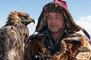 鷹獵人身穿傳統皮草裝備，手臂上站著金雕，在戶外。 — 野生動物 壁紙
