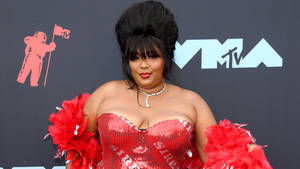 一位女性在MTV VMAs上身穿紅色亮片連衣裙搭配羽毛袖。 — 麗珠 壁紙
