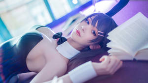 一位穿著cosplay的人躺在沙發上，手裡拿著一本打開的書。 — 櫻島麻衣 壁紙