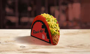木桌上品牌套筒中的 Flamin' Hot Doritos Locos Taco — 塔可 壁紙