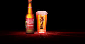 Budweiser啤酒瓶和帶有世界盃獎盃設計的杯子在紅色表面上發光。