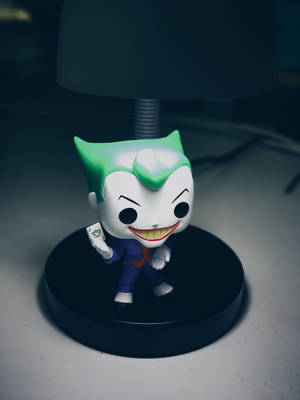 Funko Pop 小丑公仔在桌上燈下拿著小丑牌。 — 黑白小丑 壁紙