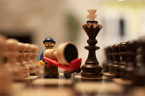 LEGO人偶在木板上推動倒下的棋子，靠近國王棋子。 — 樂高 壁紙
