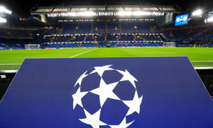 夜晚空足球場前藍色板上的UEFA歐冠標誌 — 歐洲冠軍聯賽 壁紙