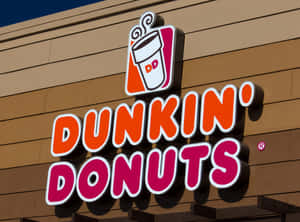 Dunkin' Donuts店面招牌，帶有咖啡杯標誌，位於米色建築物上。 — Dunkin Donuts 壁紙