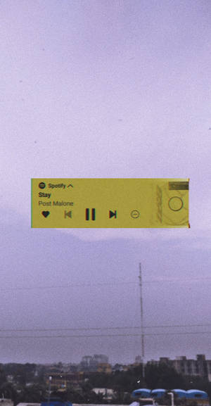 一個漂浮的 Spotify 音樂播放器，位於城市天際線之上，天空呈紫色。